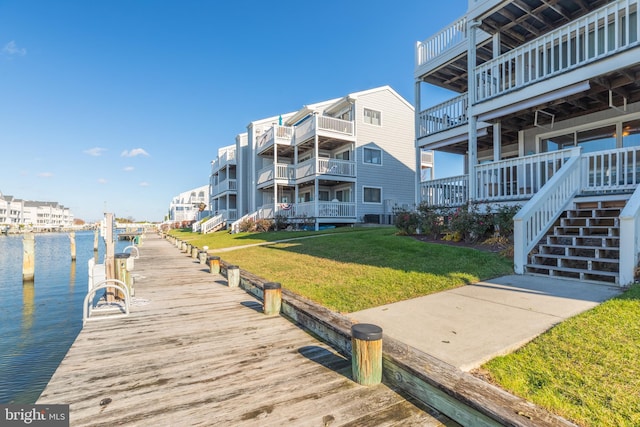 view of dock with a water view and a lawn