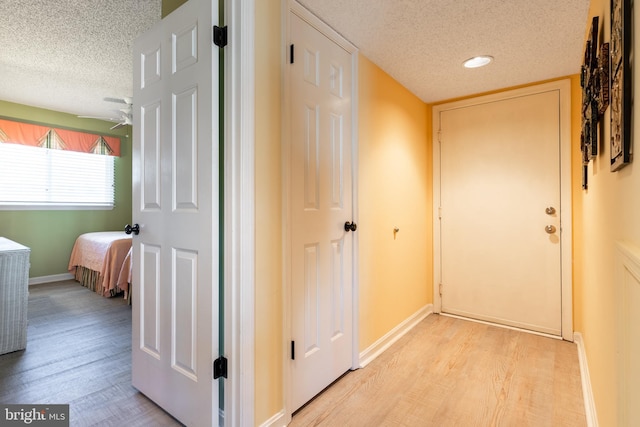 hall with a textured ceiling and light hardwood / wood-style flooring