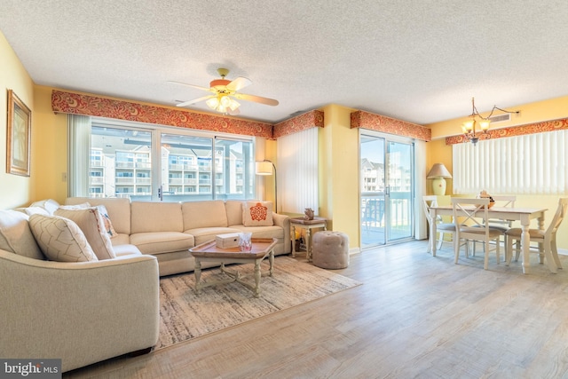 living room with ceiling fan with notable chandelier, a textured ceiling, and hardwood / wood-style flooring