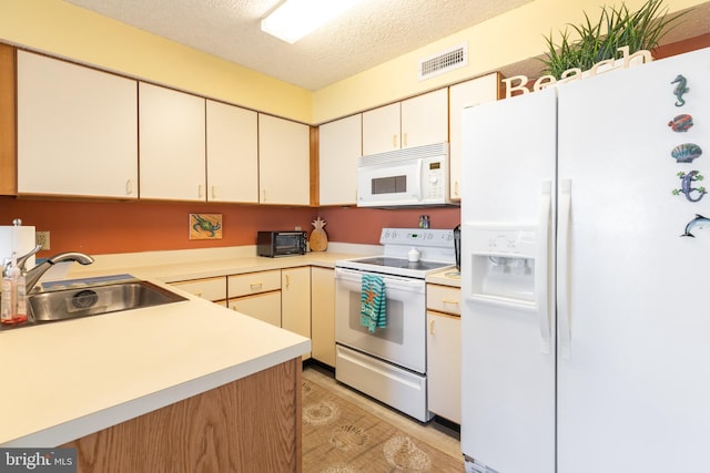 kitchen featuring a textured ceiling, sink, and white appliances