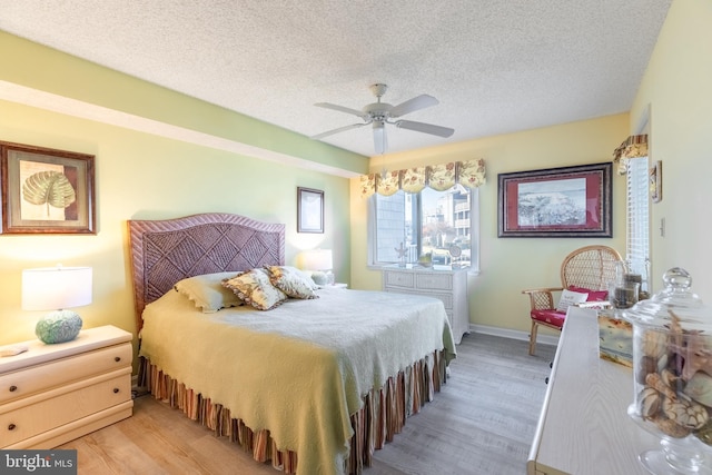 bedroom with ceiling fan, a textured ceiling, and light hardwood / wood-style flooring