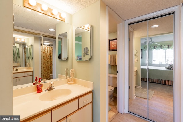 bathroom with hardwood / wood-style flooring, vanity, toilet, and a textured ceiling