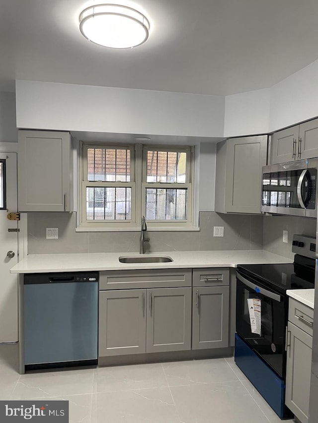 kitchen featuring sink, stainless steel appliances, gray cabinetry, and light tile patterned floors