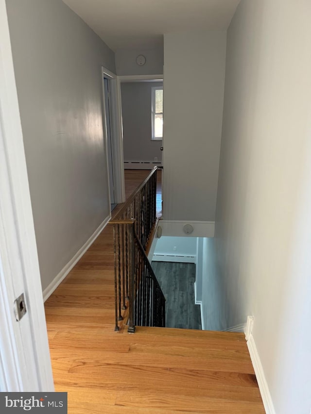 stairs featuring a baseboard radiator and hardwood / wood-style floors