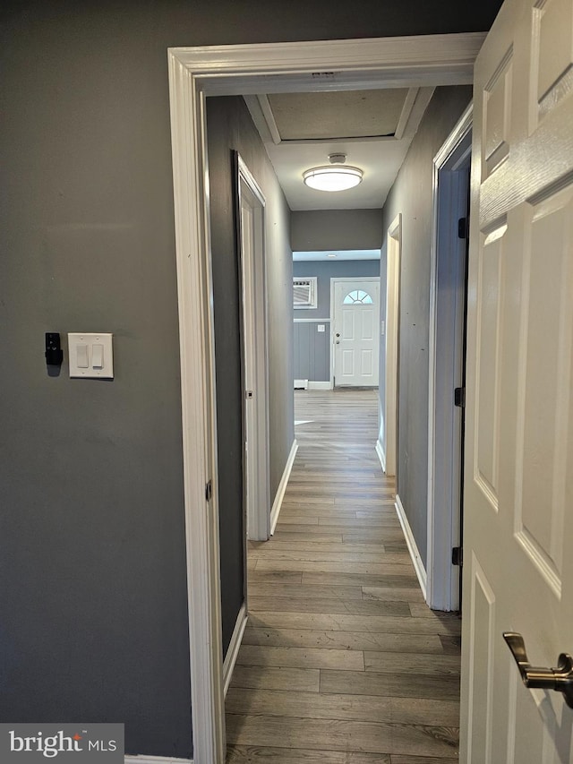 hallway with an AC wall unit and wood-type flooring