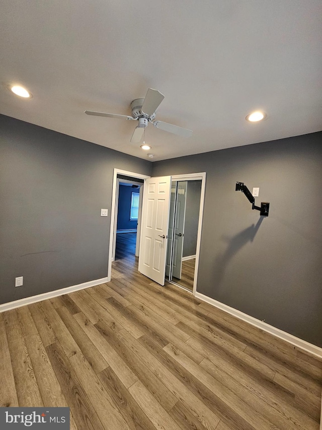 unfurnished bedroom featuring hardwood / wood-style floors, a closet, and ceiling fan