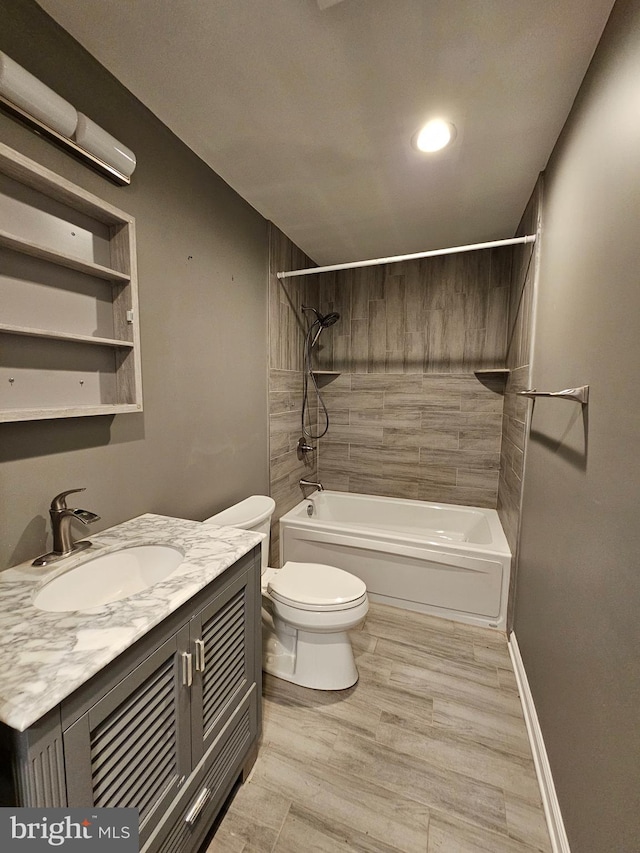 full bathroom featuring hardwood / wood-style flooring, tiled shower / bath combo, toilet, and vanity