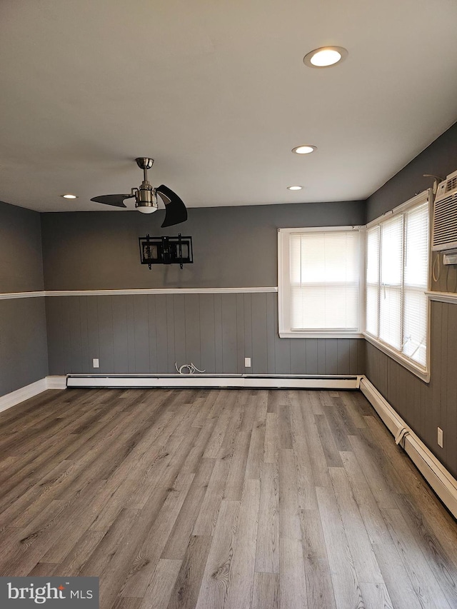 unfurnished dining area with wood-type flooring, an AC wall unit, and ceiling fan