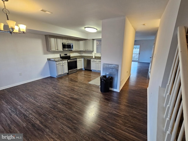 kitchen with gray cabinetry, stainless steel appliances, decorative light fixtures, a notable chandelier, and dark hardwood / wood-style floors