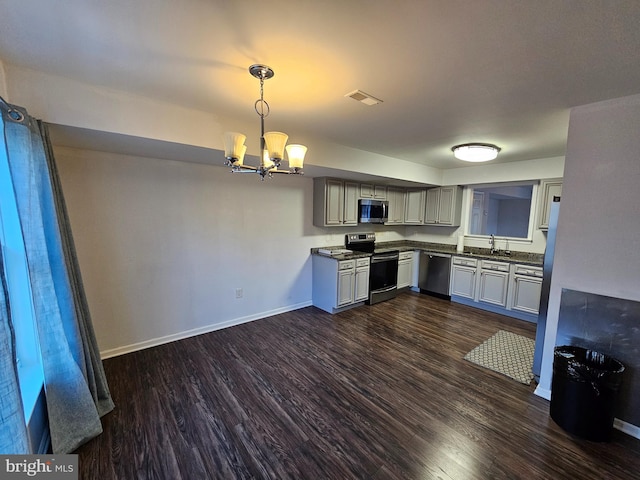 kitchen with appliances with stainless steel finishes, dark hardwood / wood-style flooring, sink, decorative light fixtures, and an inviting chandelier