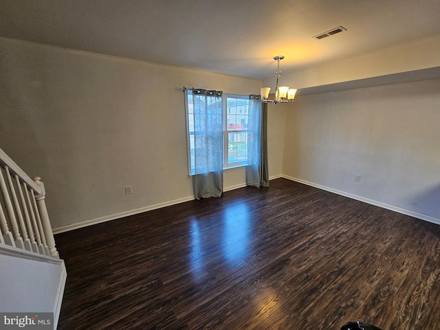 empty room with dark hardwood / wood-style flooring and a notable chandelier