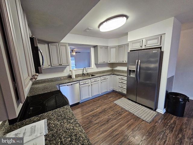 kitchen featuring dark stone counters, sink, ceiling fan, dark hardwood / wood-style flooring, and stainless steel appliances