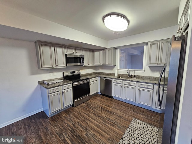 kitchen with gray cabinetry, sink, stainless steel appliances, and dark wood-type flooring