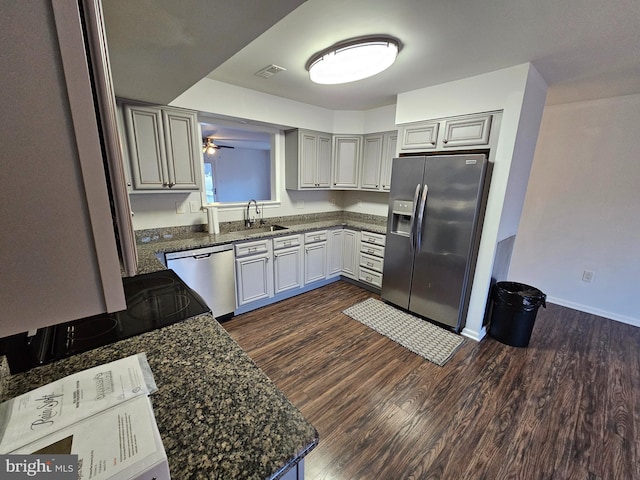 kitchen featuring sink, ceiling fan, dark stone countertops, appliances with stainless steel finishes, and dark hardwood / wood-style flooring