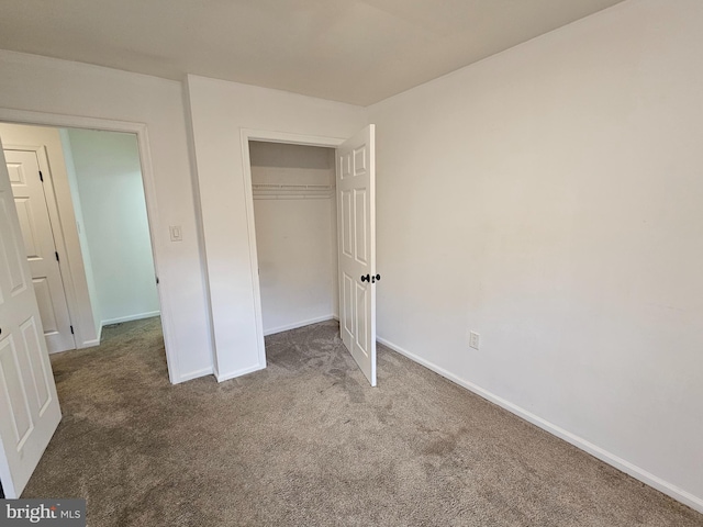 unfurnished bedroom featuring dark colored carpet and a closet