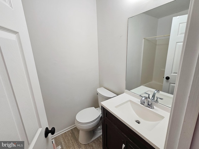 bathroom with hardwood / wood-style floors, vanity, toilet, and walk in shower