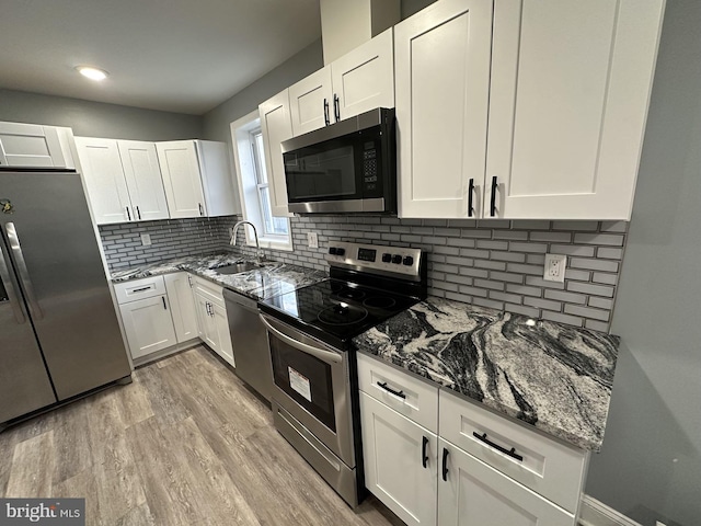 kitchen with white cabinets, stainless steel appliances, and light hardwood / wood-style flooring