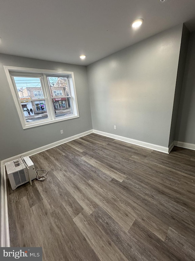 empty room featuring dark hardwood / wood-style floors and an AC wall unit