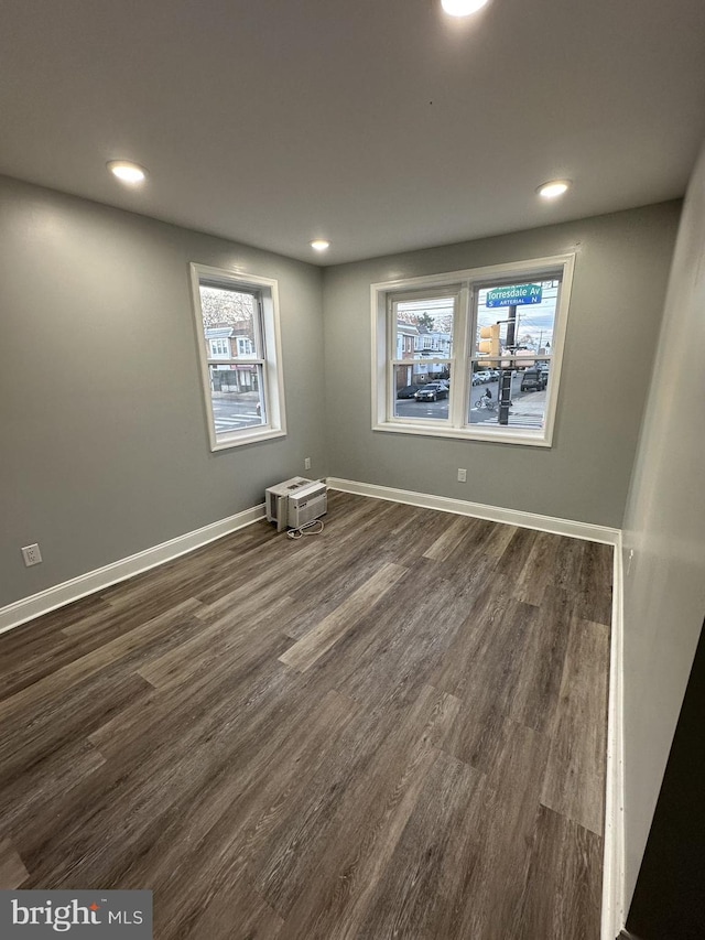 unfurnished room featuring plenty of natural light and dark wood-type flooring