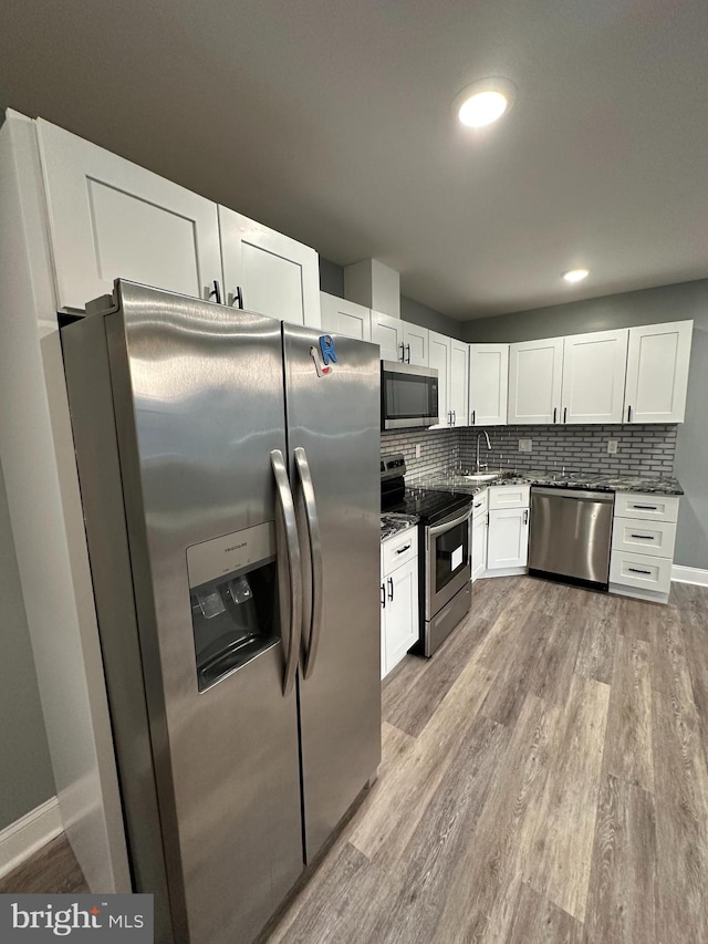 kitchen featuring decorative backsplash, light hardwood / wood-style floors, white cabinetry, and appliances with stainless steel finishes