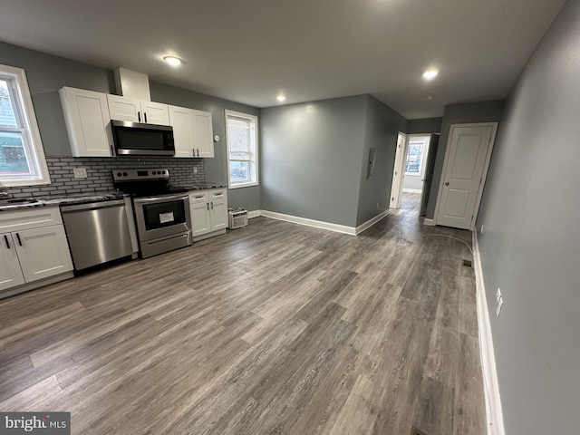 kitchen with appliances with stainless steel finishes, white cabinetry, and hardwood / wood-style floors