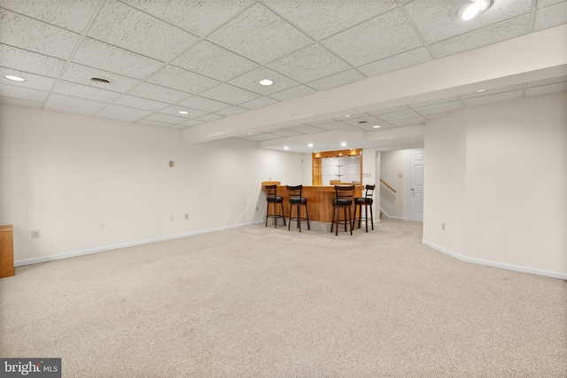 interior space with light carpet, bar area, and a drop ceiling