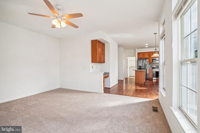 unfurnished living room featuring dark hardwood / wood-style flooring, washer / clothes dryer, plenty of natural light, and ceiling fan