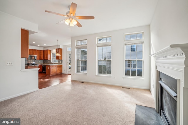 unfurnished living room with dark carpet and ceiling fan