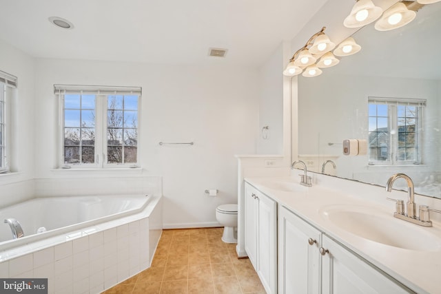 bathroom with tile patterned floors, vanity, toilet, and tiled tub