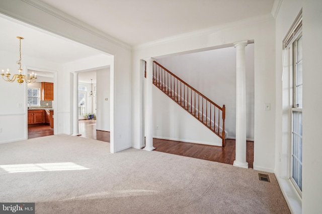 entrance foyer featuring ornamental molding, dark carpet, and a notable chandelier