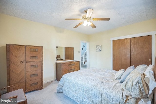 bedroom with ceiling fan, a textured ceiling, and light carpet