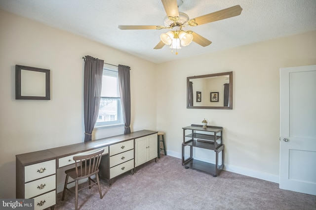 carpeted office space with ceiling fan, built in desk, and a textured ceiling