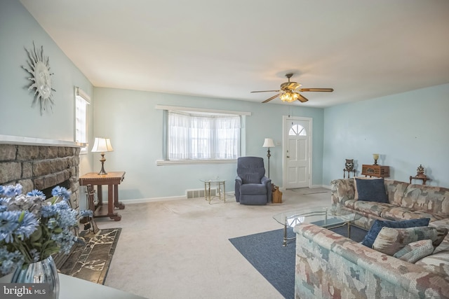 living room with carpet flooring, a stone fireplace, and ceiling fan