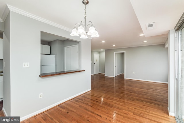 empty room featuring hardwood / wood-style floors, an inviting chandelier, and crown molding