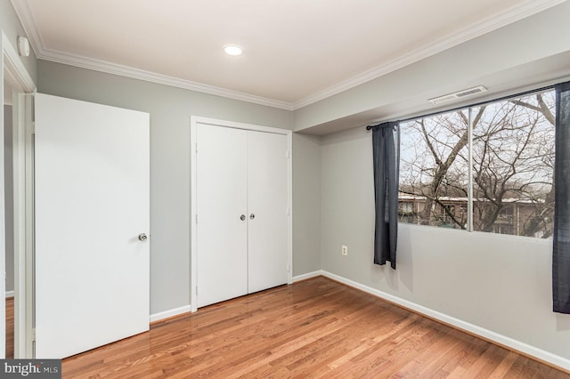 unfurnished bedroom featuring light wood-type flooring, a closet, and crown molding