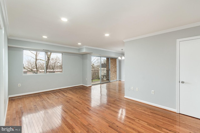 spare room featuring a notable chandelier, light wood-type flooring, and ornamental molding