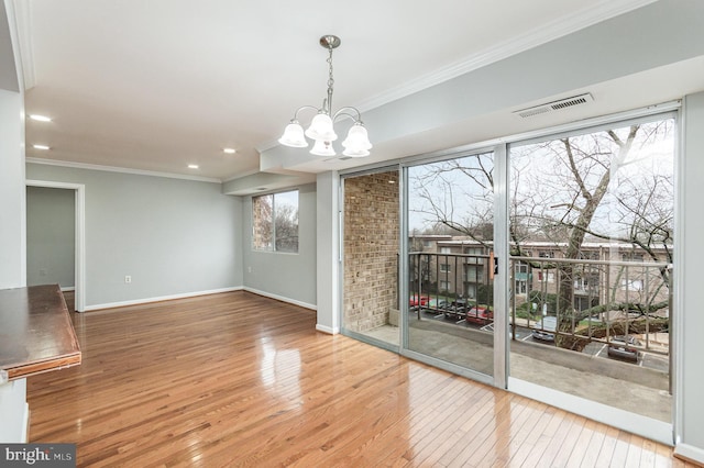 interior space featuring wood-type flooring, ornamental molding, and a notable chandelier