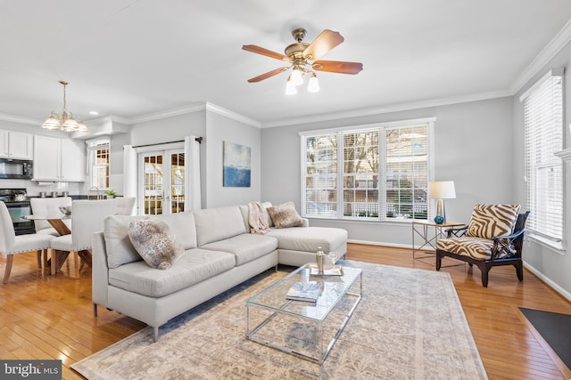 living room featuring ceiling fan with notable chandelier, light hardwood / wood-style floors, and crown molding