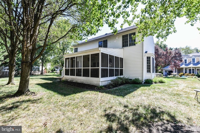 back of property featuring a yard and a sunroom