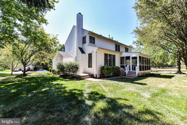 rear view of house featuring a yard and a sunroom