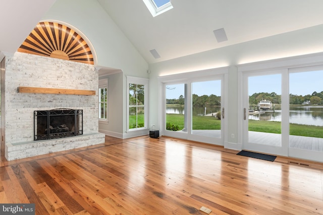 unfurnished living room featuring a water view, a fireplace, high vaulted ceiling, and hardwood / wood-style floors