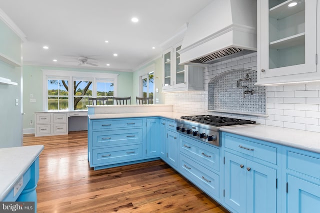 kitchen with stainless steel gas cooktop, light countertops, ornamental molding, blue cabinetry, and custom exhaust hood