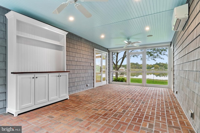 unfurnished sunroom featuring an AC wall unit, a water view, ceiling fan, and wooden ceiling