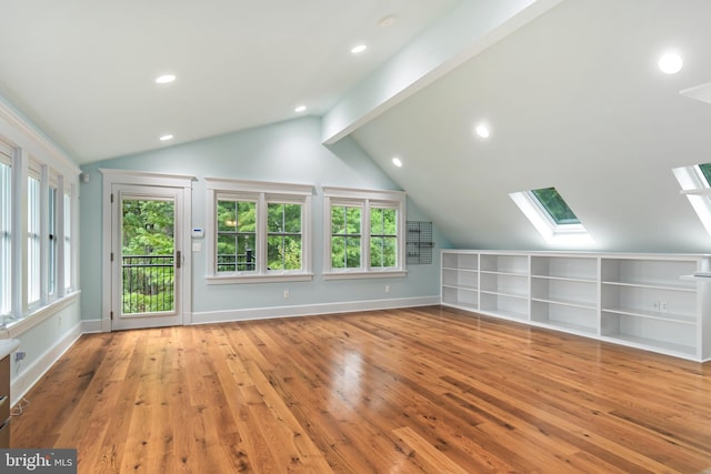 bonus room featuring vaulted ceiling with skylight, hardwood / wood-style floors, recessed lighting, and baseboards