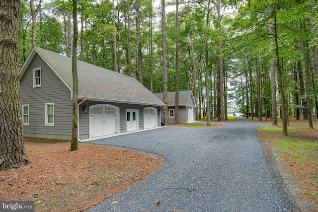 view of front of property with a shingled roof, gravel driveway, and a garage