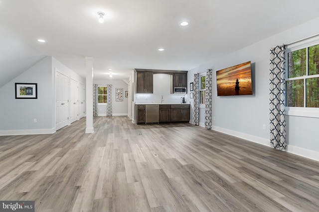 unfurnished living room featuring light wood finished floors, plenty of natural light, and baseboards