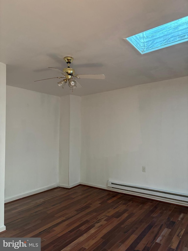 unfurnished room with ceiling fan, dark hardwood / wood-style flooring, baseboard heating, and a skylight