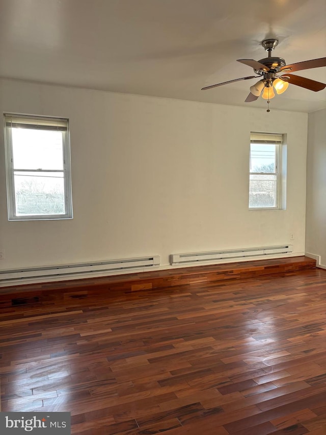 unfurnished room featuring ceiling fan, baseboard heating, dark wood-type flooring, and a wealth of natural light