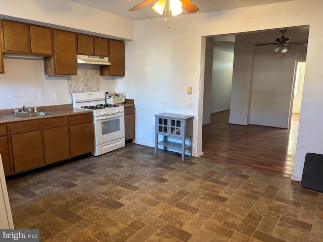 kitchen with ceiling fan, sink, white gas range oven, and dark wood-type flooring