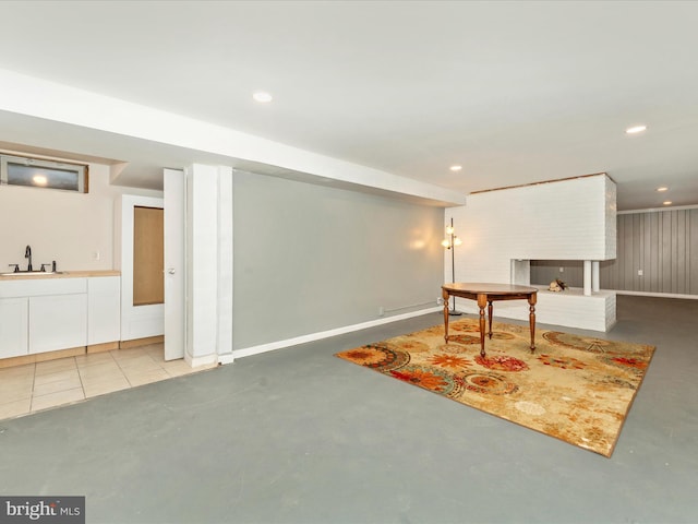 rec room with a brick fireplace, sink, wooden walls, and concrete floors